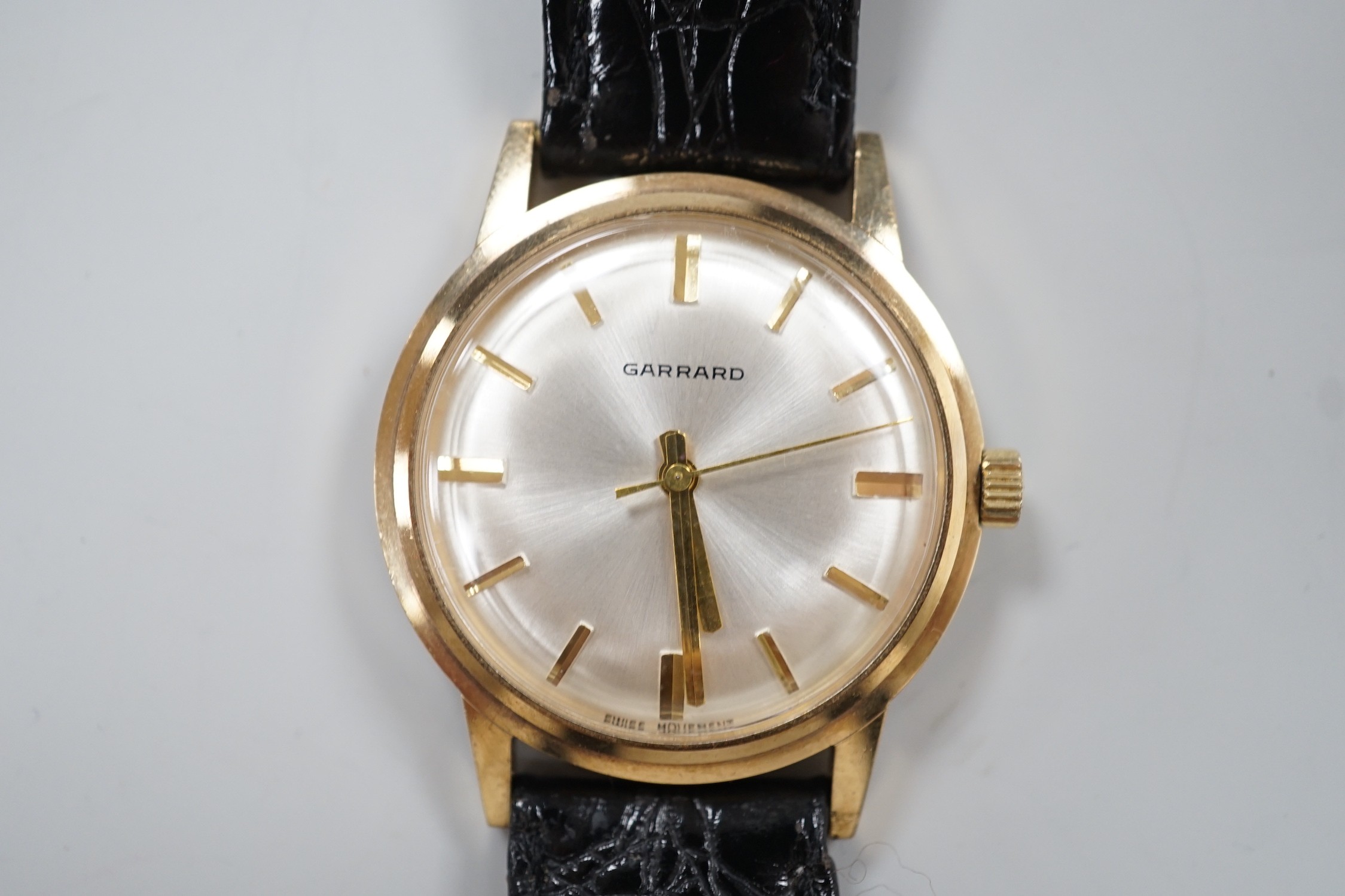 A gentleman's 1970's yellow metal Garrard manual wind wrist watch, with case back inscription, on a leather strap, case diameter 35mm, in Garrards box.